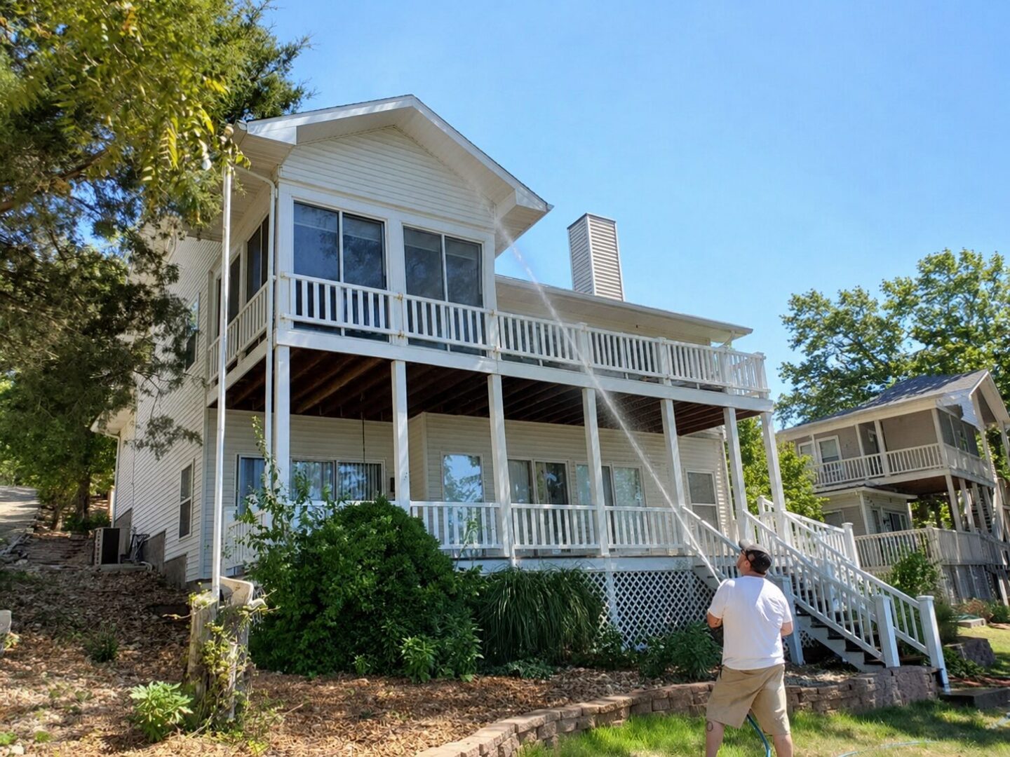 Person spraying water at two-story house