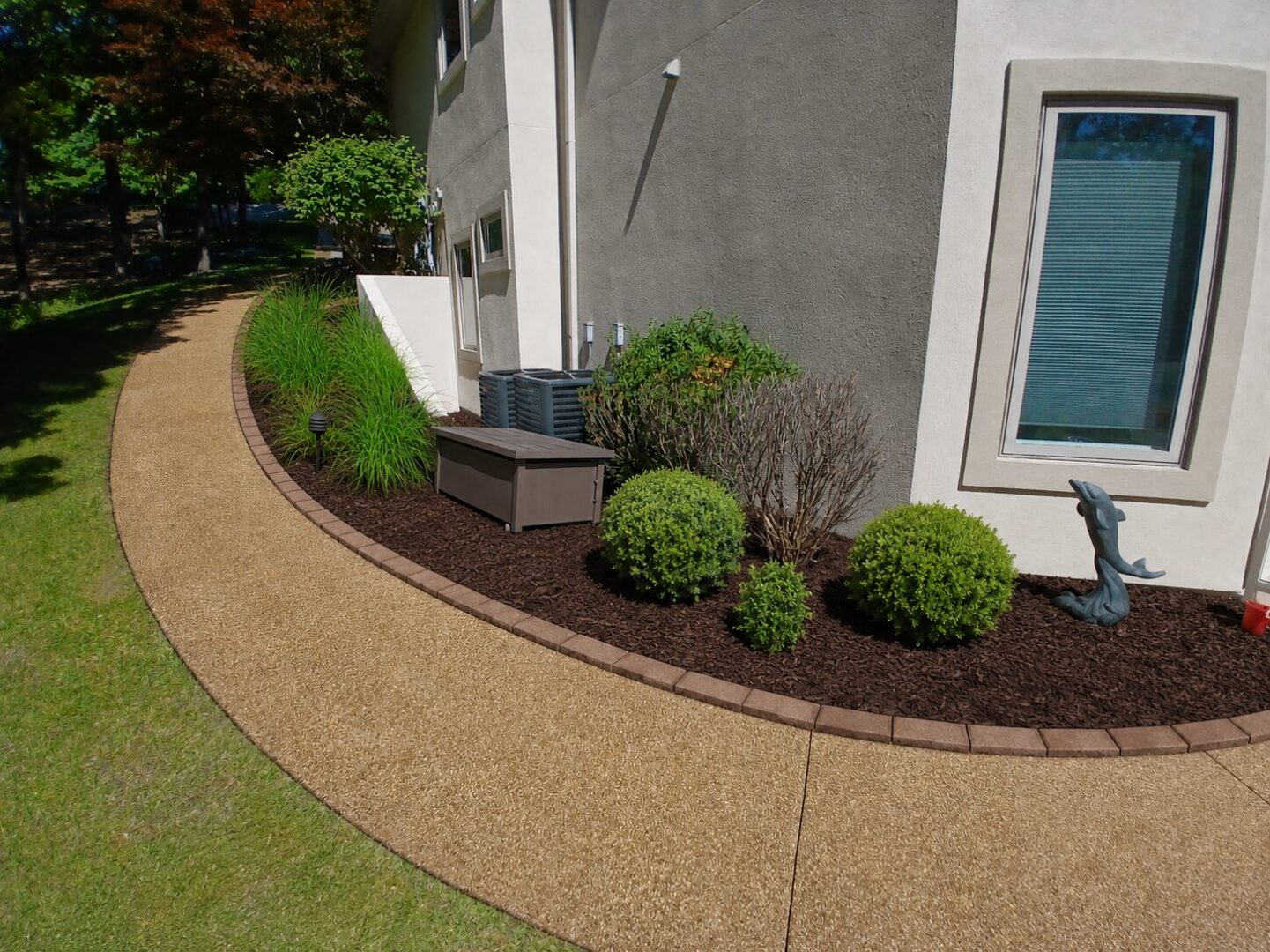 Decorative dolphin by landscaped mulch bed and path